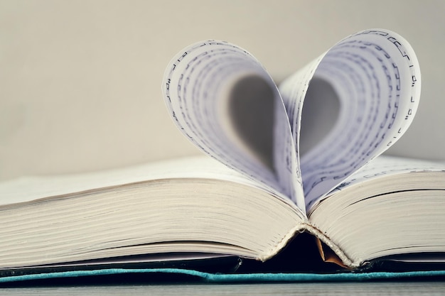 Book pages curved into heart shape on gray background