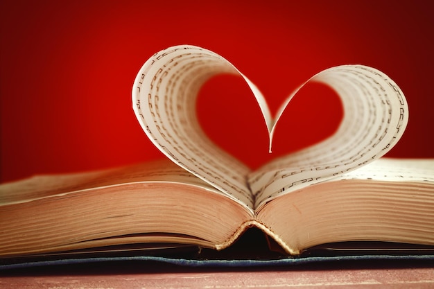 Book pages curved into heart shape on pink background