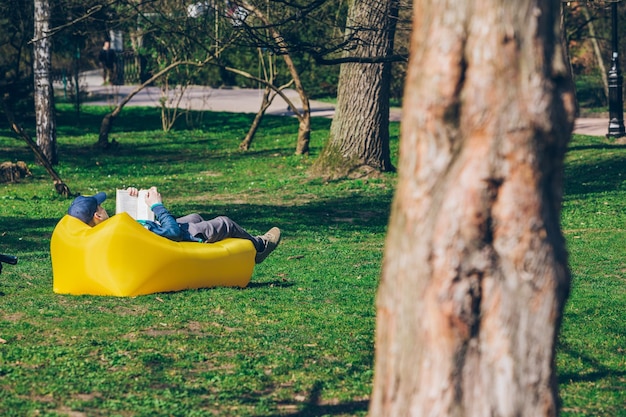 book reading concept man in city park on inflatable mattress