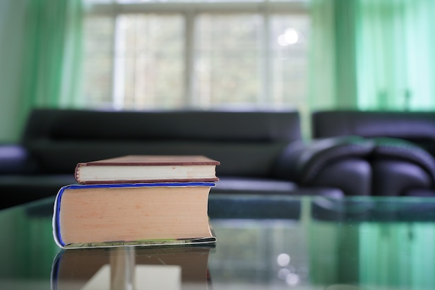 book stack on top glass table with blur sofa set in living room