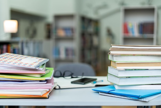 Book stack on wood desk and blurred bookshelf in the library room education background back to school concept