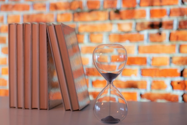 Books arranged on a shelf with an hourglass in the foreground