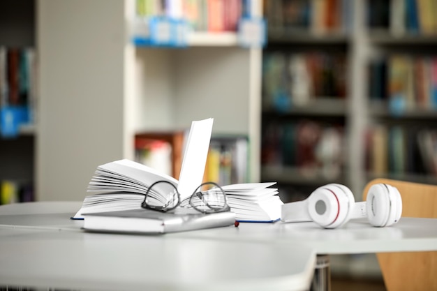 Books glasses and headphones on table in library