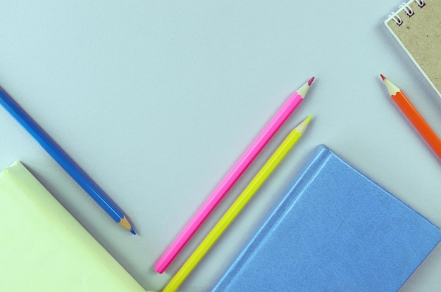 Books, sketchbook and colorful pencils on the table, top view, save space