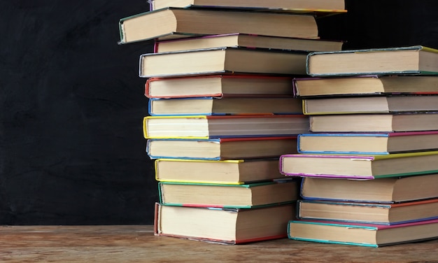 Books in stacks on the table of a school blackboard. 