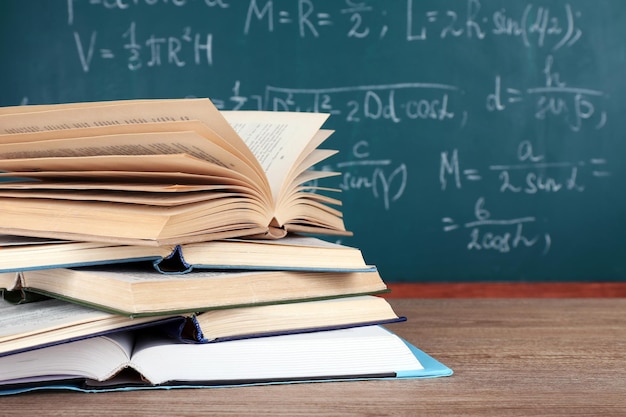 Books on wooden table on blackboard background