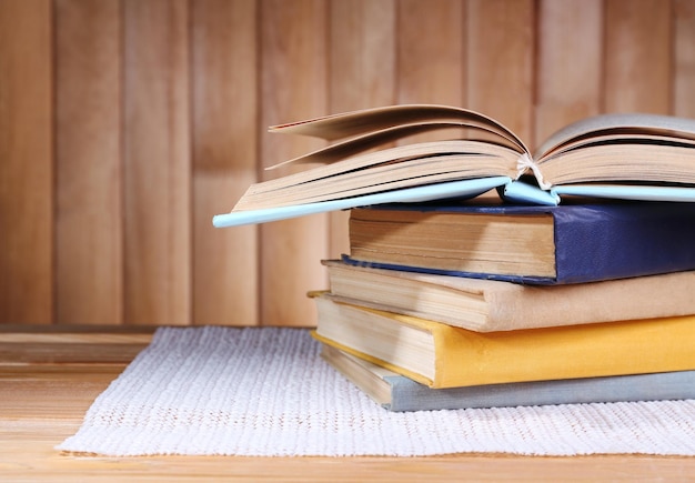 Books on wooden table on wooden wall background