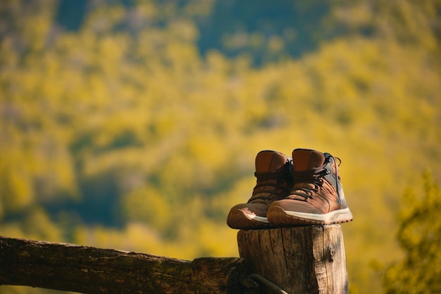 Boots of a hiker leaning on a pole with a mountain in the background after an excursion