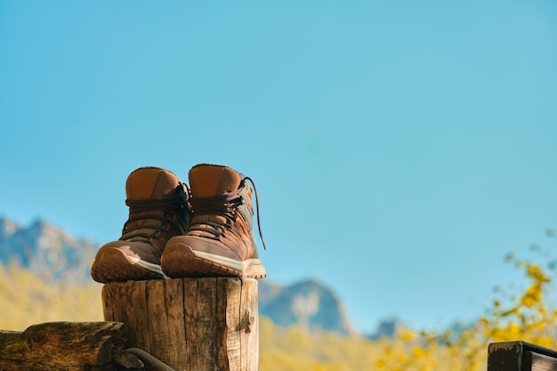 Boots of a hiker leaning on a pole with the sky in the background after an excursion