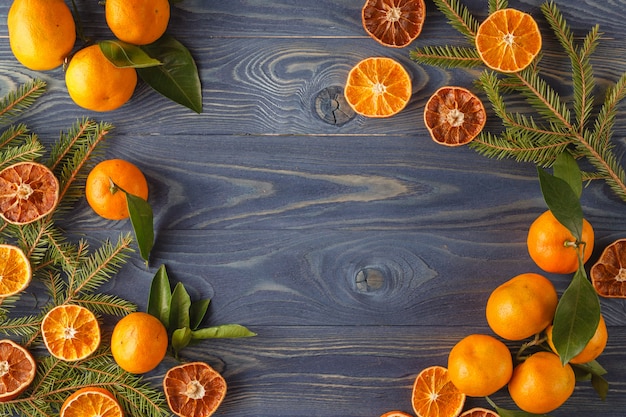 Border, frame from Christmas tree fir branches, dried orange fruit slice on old wooden desk table background.