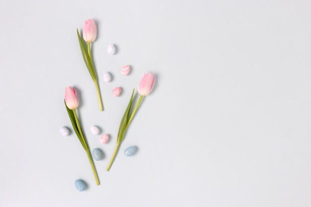 Border frame made of easter eggs and flowers on a blue pastel background