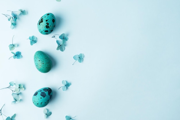 Border made of Easter quail eggs with hydrangea flowers on a blue background Easter greeting card