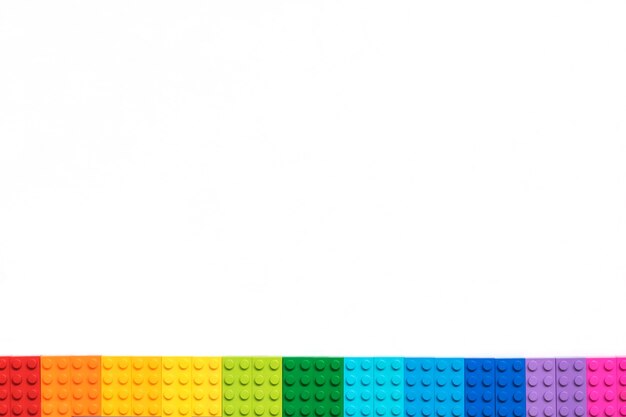 Photo border of multicolor plastick constructor bricks on white background. popular toys.