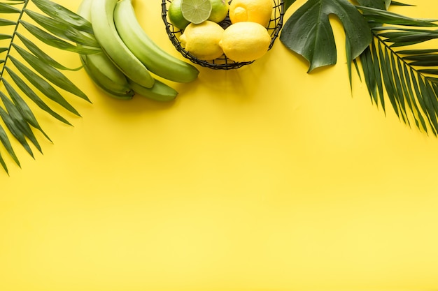 Border of tropical beach outfit, female accessories, straw sun hat, monstera leaves on yellow. Summer concept.