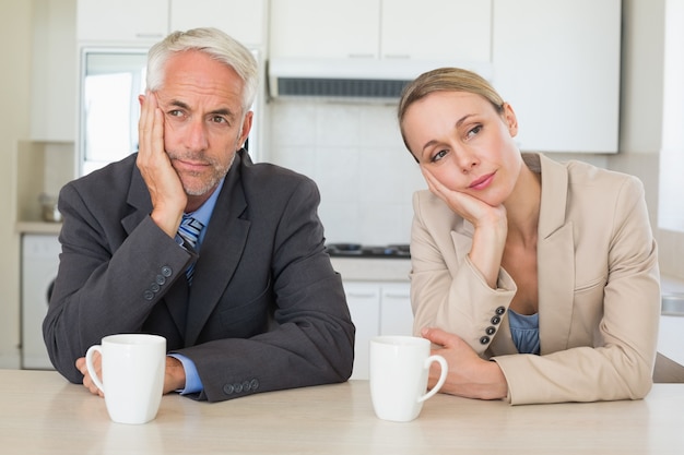 Bored business couple having coffee before work in morning