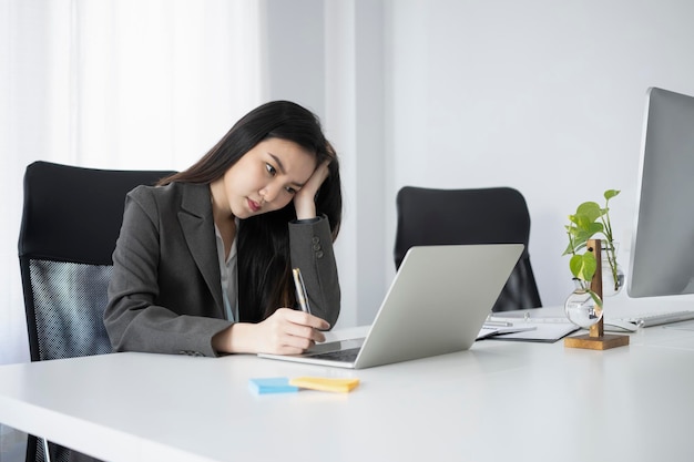 Bored female office worker working with laptop computer at office.