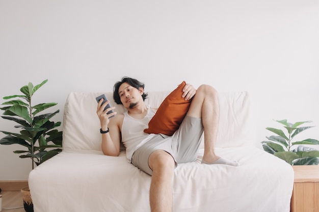 Bored man relaxed and use smartphone for killing time alone in apartment