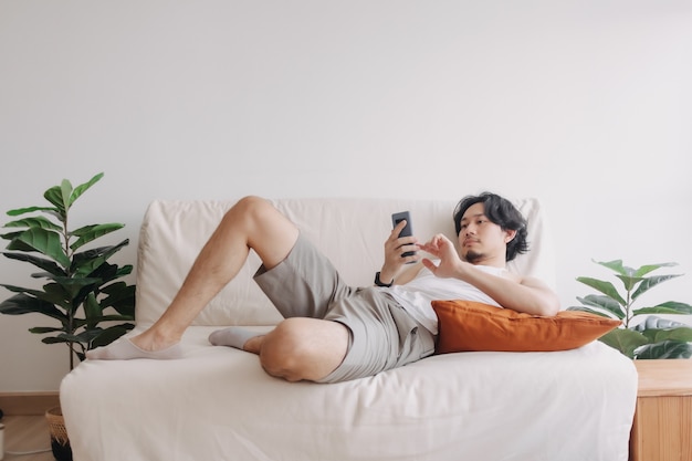 Bored man relaxed and use smartphone for killing time alone in apartment