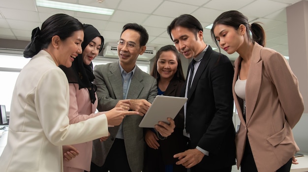 Boss explains the project by tablet to the business team in a modern office.