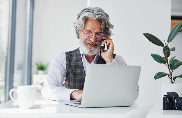 Boss in formal clothes works in office Senior stylish modern man with grey hair and beard indoors