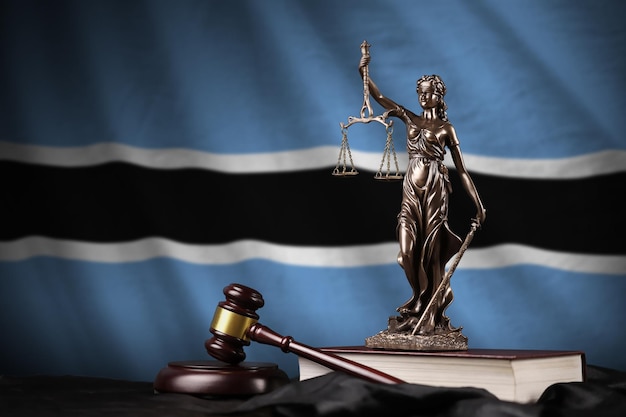 Botswana flag with statue of lady justice constitution and judge hammer on black drapery Concept of judgement and guilt