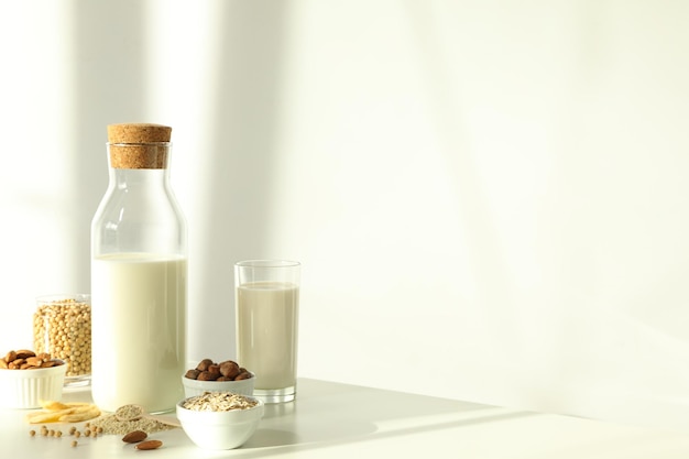 Bottle of alternative milk and herbal ingredients on light background space for text