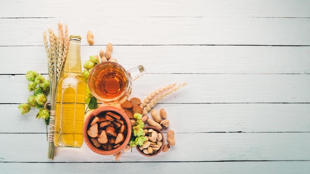 A bottle of beer Hops beer chips nuts On a white wooden background Free space for text Top view