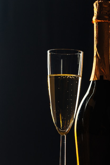 Bottle of champagne and glasses over dark 