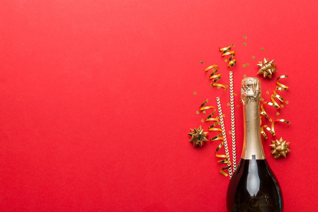 Bottle of champagne with glasses and colorful confetti on colored background top view flay lay