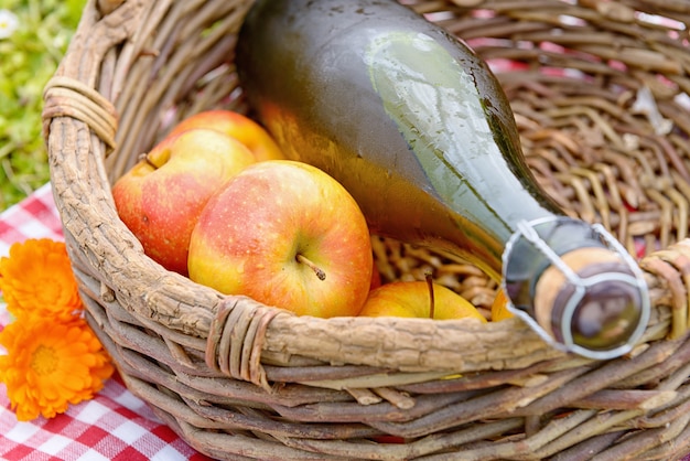 bottle of cider with apples in a basket