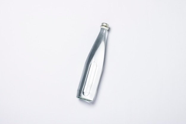 Bottle of clear crystal water on a white background under the sunlight. The concept of thirst, heat, summer, tropic. Flat lay, top view