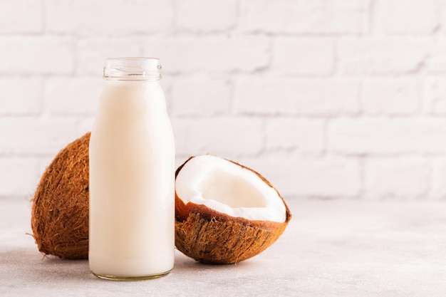 A bottle of coconut milk and coconut on a light background.