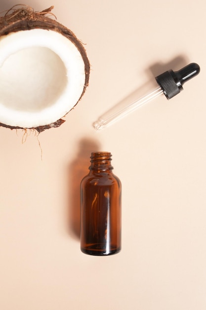 Bottle of coconut oil and fresh coconuts on beige background Coconut natural cosmetics