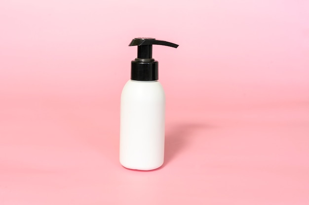 Bottle for cream with dispenser on pink background