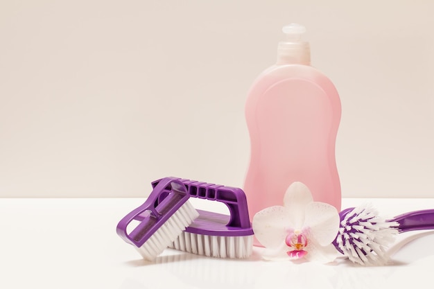 Bottle of dishwashing liquid and brushes on white background