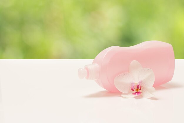 Bottle of dishwashing liquid and orchid on blurred background