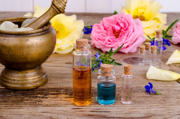 Bottle of essential oil for aromatherapy with fresh rose flowers.