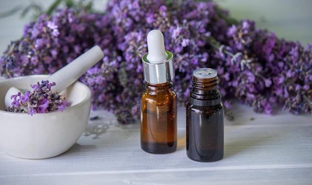 A bottle of essential oil with fresh blooming lavender twigs