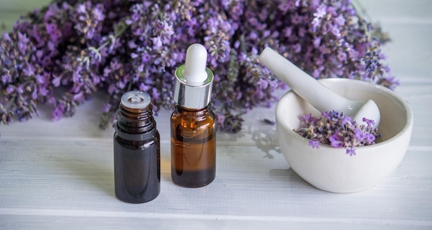 A bottle of essential oil with fresh blooming lavender twigs