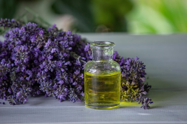 A bottle of essential oil with fresh blooming lavender twigs