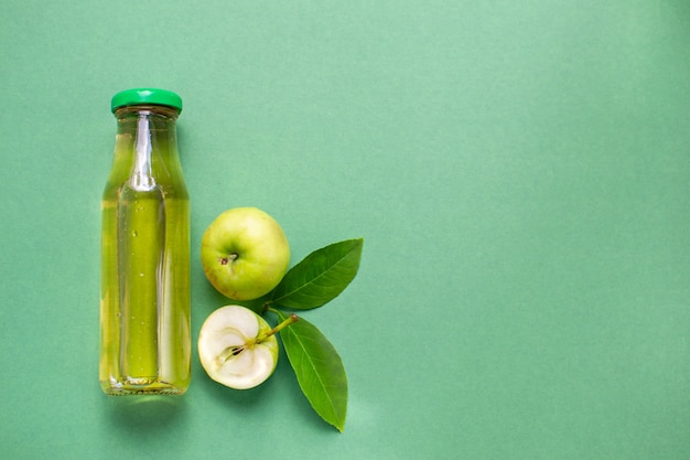 bottle of fresh apple juice fruit pattern flat lay  top view green background with copy space