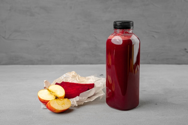 Bottle of fresh beet juice on gray surface