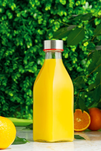 Bottle of fresh orange juice with fresh fruits over a green background