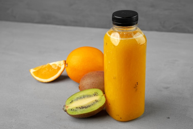 Bottle of freshly squeezed orange juice on gray table