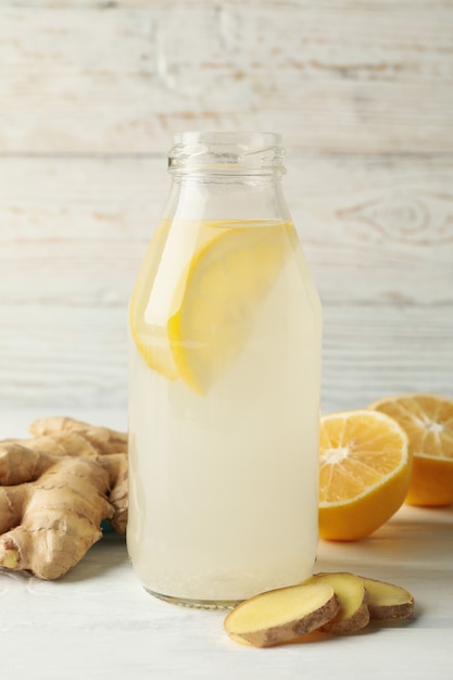 Bottle of ginger lemon water on white wooden background