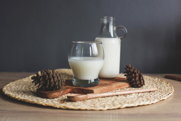 Bottle and glass of tasty milk on wooden board