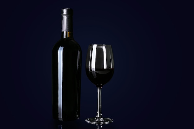 Bottle and glass with red wine on black background