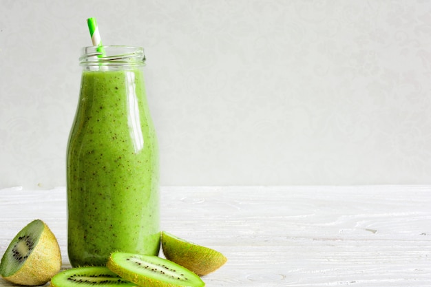 Bottle of green smoothie with fresh kiwi and banana fruits and berries