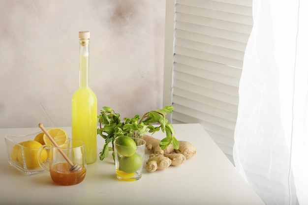 Bottle of homemade juice with ginger and lemon on light background Horizontal