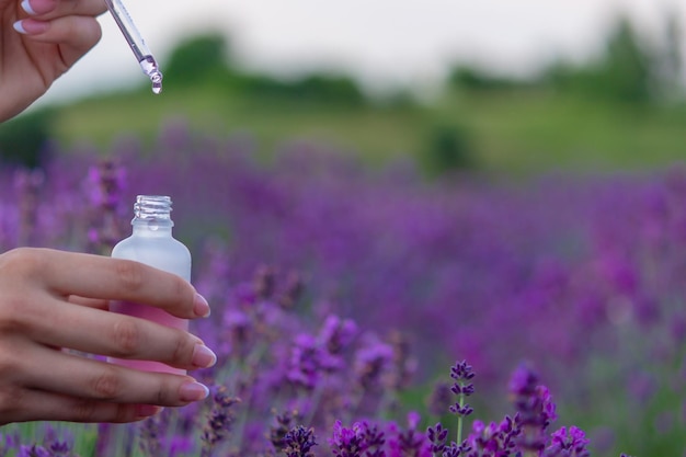 A bottle of lavender essential oil on a wooden table and a field of flowers background